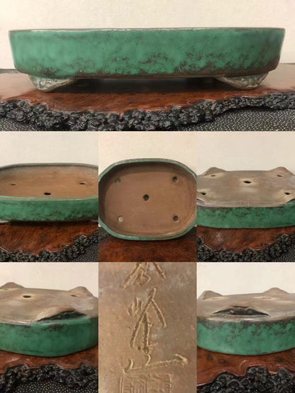A green glazed pot with a brown interior, four drainage holes, and an engraved mark on its base.