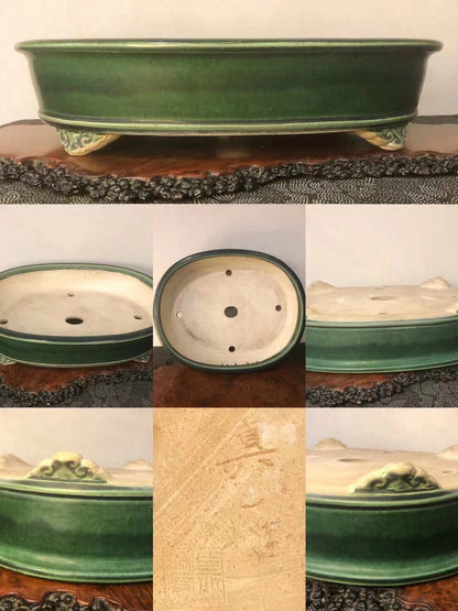Dark green glazed oval pot with three footed bases and a carved signature on the side.