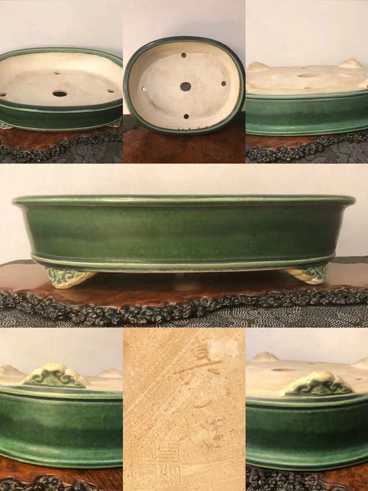 Dark green glazed oval pot with three footed bases and a carved signature on the side.