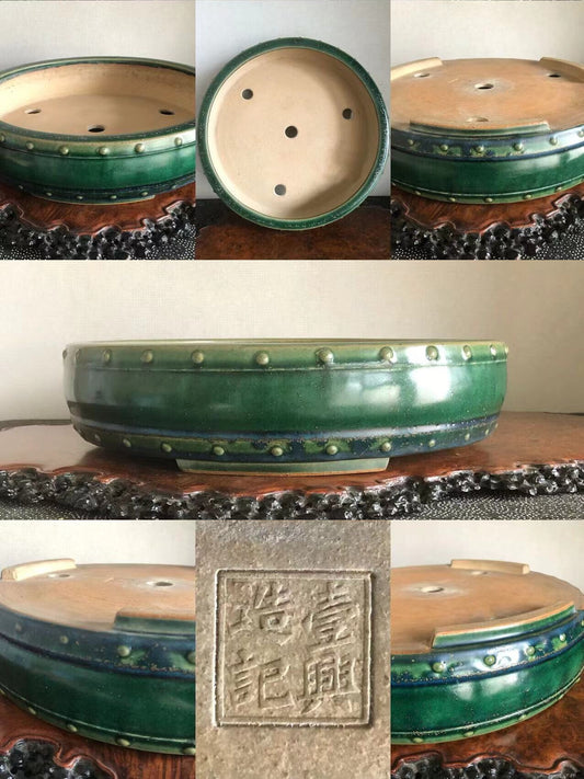 A green glazed ceramic bonsai pot with raised dots and a square stamped mark.