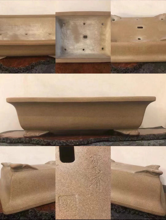 A beige, rectangular bonsai pot with carved characters and a glossy finish.