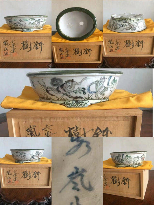 A white glazed pot with green rim, painted with dragons and clouds, sits on a wooden box.