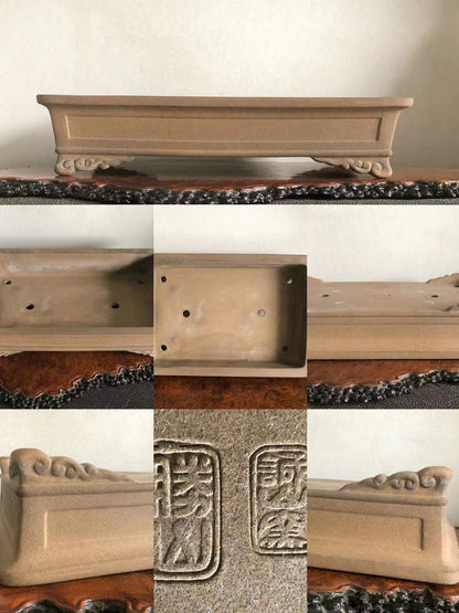 Rectangular beige ceramic pot with carved feet and two square maker’s marks on base.