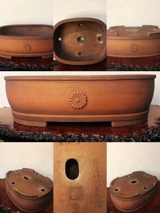 A brown glazed bonsai pot with a sunburst decoration and carved characters on its side.