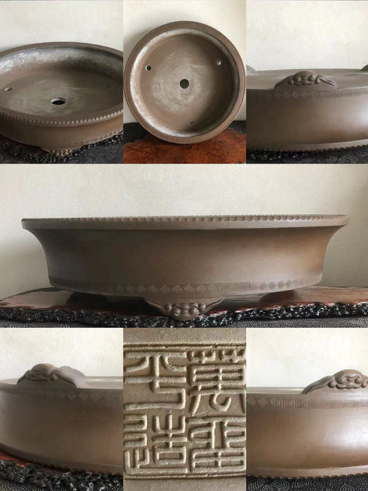 A brown glazed ceramic bonsai pot with carved dragon motifs and a raised rim.