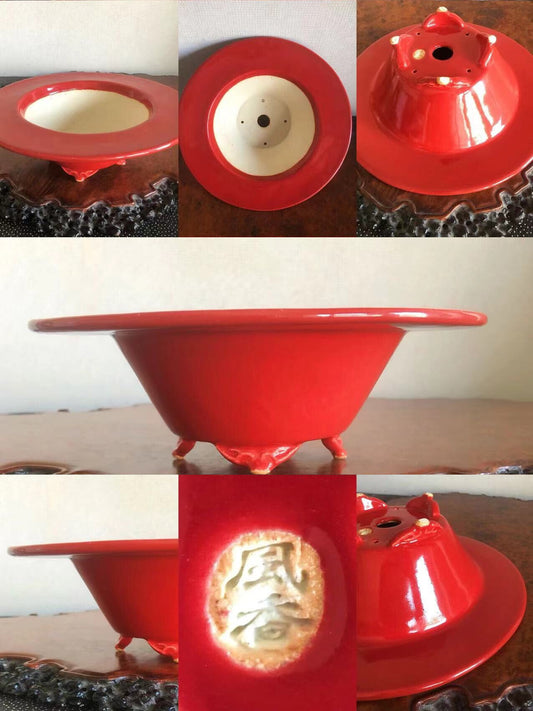 A glossy red ceramic pot with three feet and a gold-embossed character on its base.