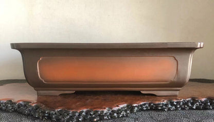 A matte brown rectangular pot with a recessed orange panel and curved rim.