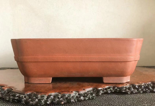 Square terracotta pot with matte finish and two horizontal ridges, resting on four short feet.