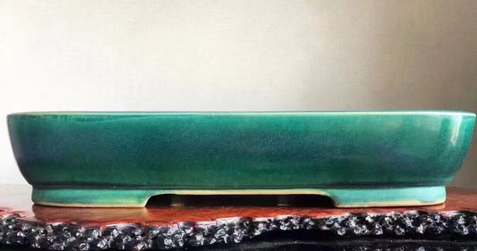 A glossy teal glazed rectangular pot with a low rim and footed base.