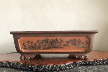 Rectangular terracotta pot with glazed brown surface, featuring a black ink landscape scene on its side.