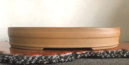 A shallow, unglazed terracotta pot with a wide rim and subtle horizontal ridges.