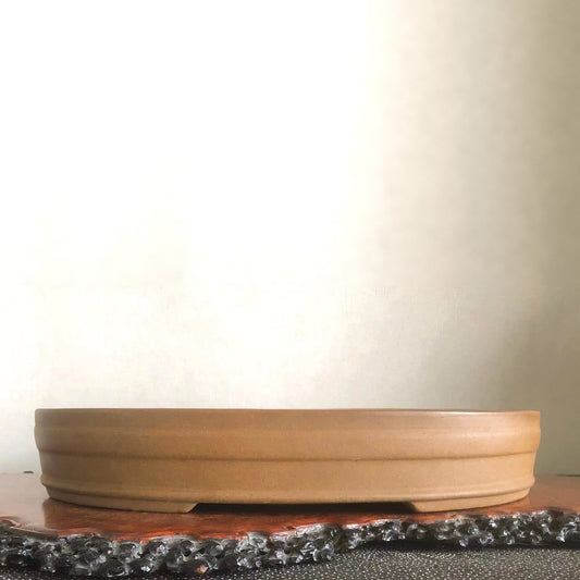 A shallow, unglazed terracotta pot with a wide rim and subtle horizontal ridges.