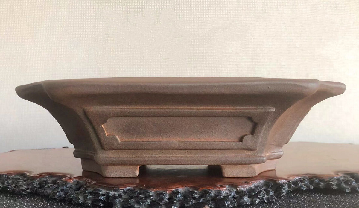 A brown, matte-finished ceramic pot with flared sides and a central recessed panel.