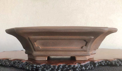 A brown, matte-finished ceramic pot with flared sides and a central recessed panel.