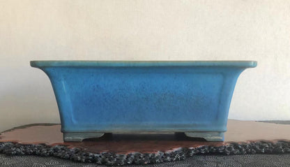 A rectangular blue glazed pot with speckled surface and slightly curved sides.
