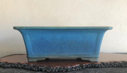 A rectangular blue glazed pot with speckled surface and slightly curved sides.