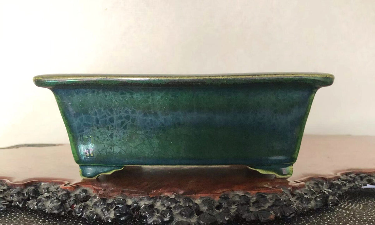 A rectangular glazed pot with a crackled dark green surface and a lighter green rim.