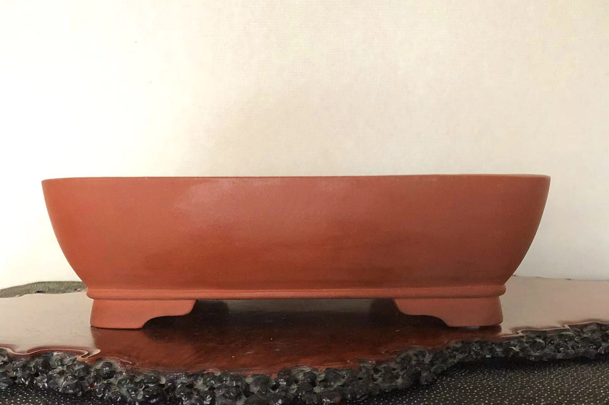 A terracotta bonsai pot with a smooth, unglazed surface and a low, rounded rim.