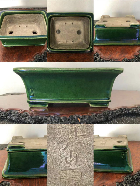 A glossy green rectangular ceramic pot with a carved signature and drainage holes.