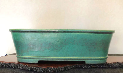A long, low, teal-glazed ceramic pot with a speckled surface and dark rim.