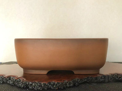A matte brown ceramic pot with a low, wide rim and a single central foot.
