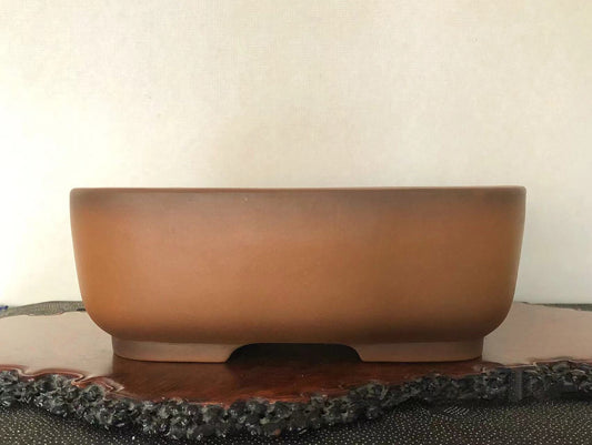 A matte brown ceramic pot with a low, wide rim and a single central foot.