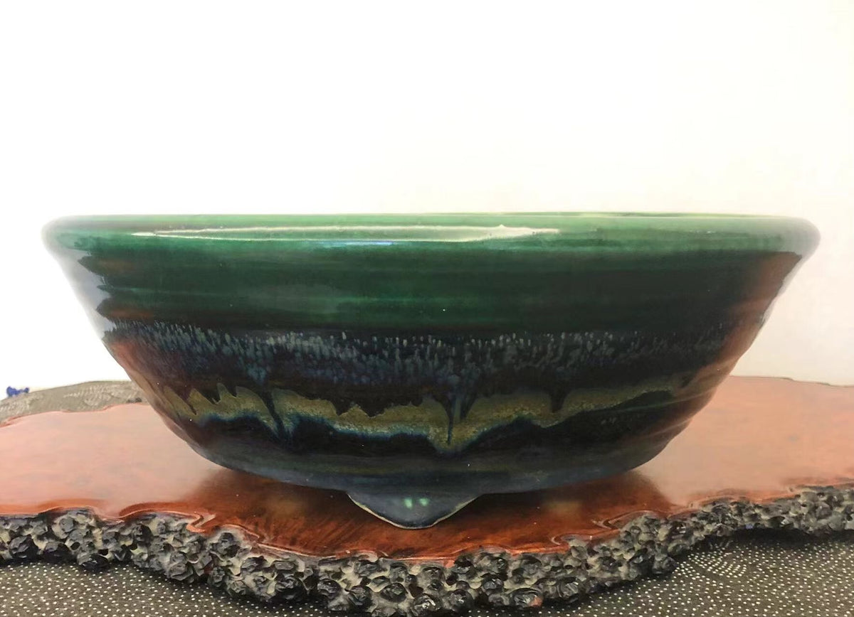 A glossy ceramic pot with a wide green rim and a dark, layered glaze interior.