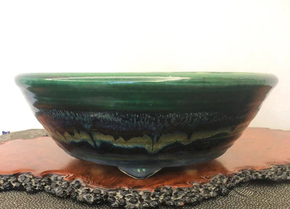 A glossy ceramic pot with a wide green rim and a dark, layered glaze interior.