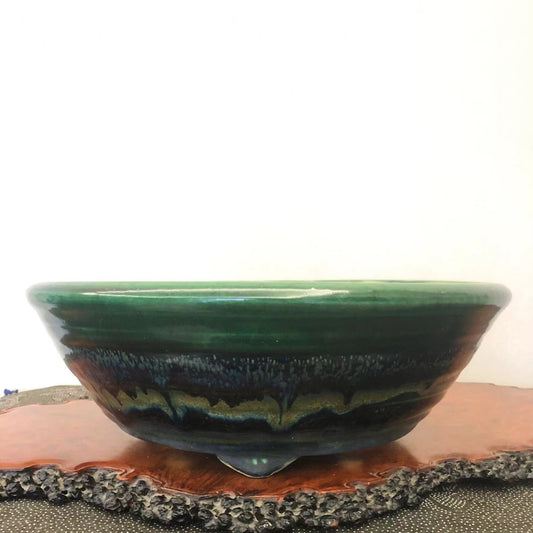 A glossy ceramic pot with a wide green rim and a dark, layered glaze interior.