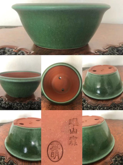 A green glazed ceramic bonsai pot with a reddish-brown unglazed interior and two drainage holes.