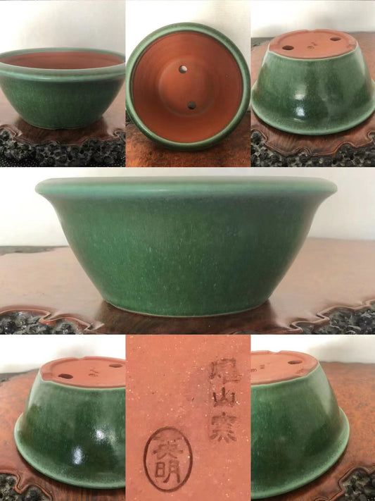 A green glazed ceramic bonsai pot with a reddish-brown unglazed interior and two drainage holes.