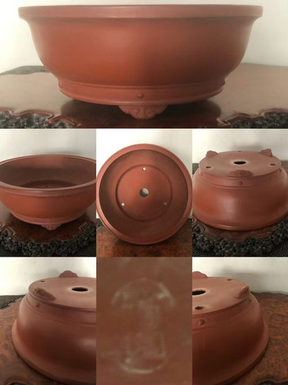A reddish-brown unglazed ceramic bonsai pot with a wide rim, footed base, and drainage holes.