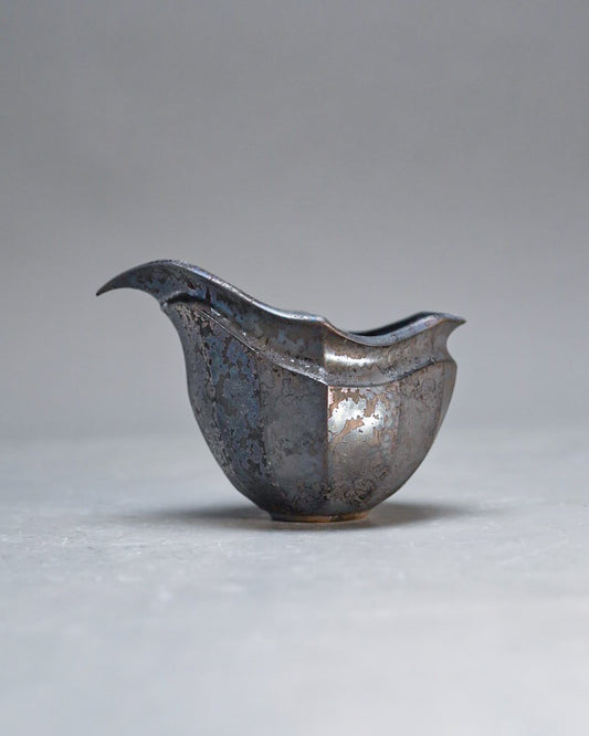 Small pouring bowl in dark metallic glaze with a sharply drawn spout and a soft silver sheen.