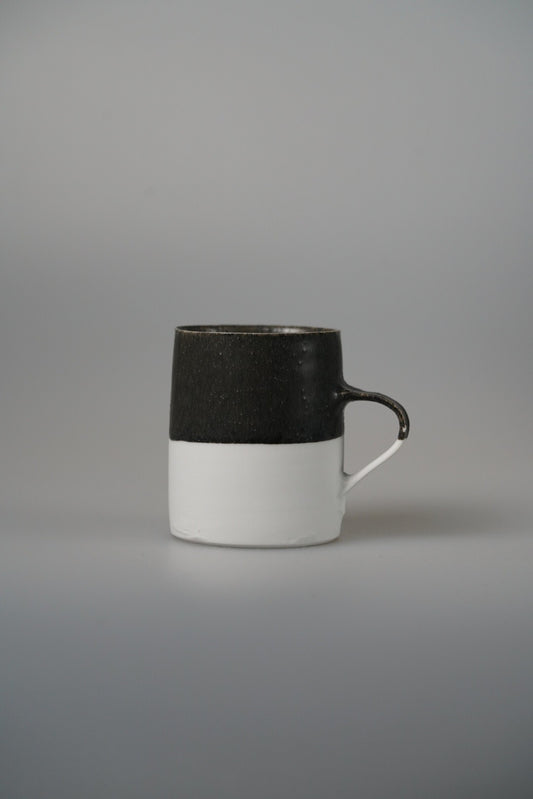 Tall mug banded matte black over white, with a slim white ring handle.