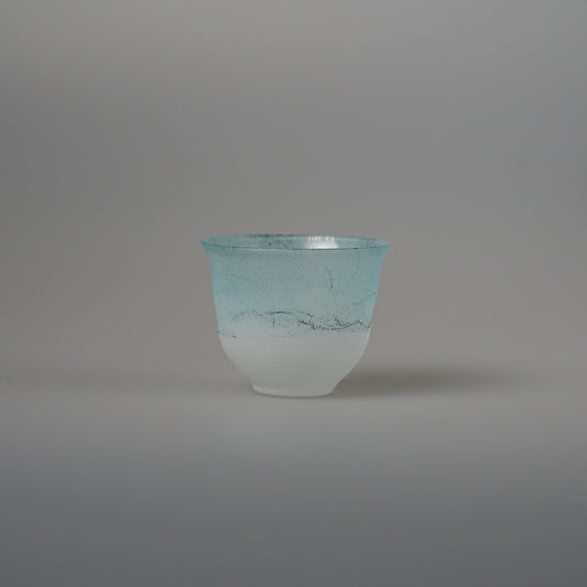 Small glass sake cup in frosted white shading to soft turquoise at the rim.
