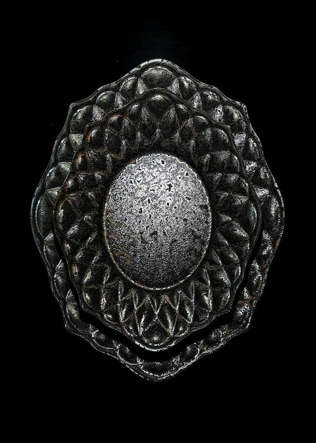 Deep black plate with a quilted diamond-cut border and a speckled metallic oval at its centre.
