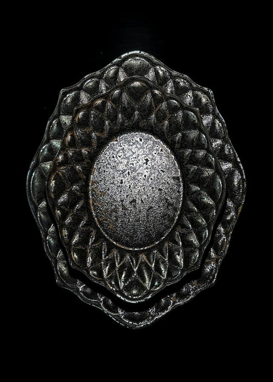 Deep black plate with a quilted diamond-cut border and a speckled metallic oval at its centre.