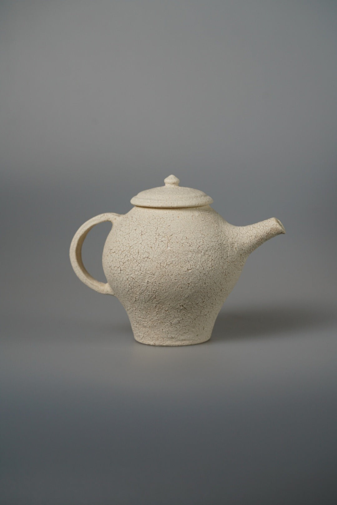 Cream teapot with a stepped conical body, a domed lid and a slim upright spout.
