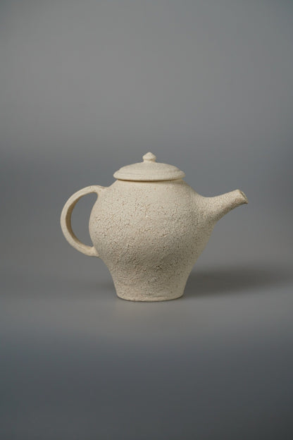 Cream teapot with a stepped conical body, a domed lid and a slim upright spout.