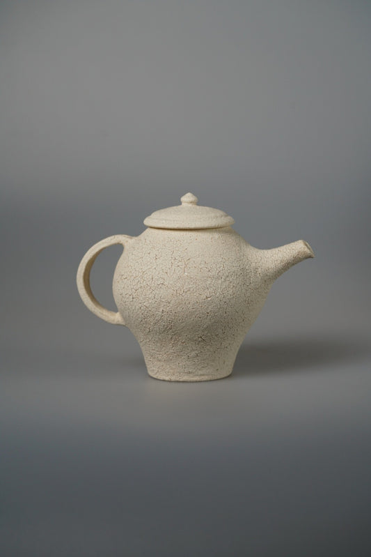 Cream teapot with a stepped conical body, a domed lid and a slim upright spout.