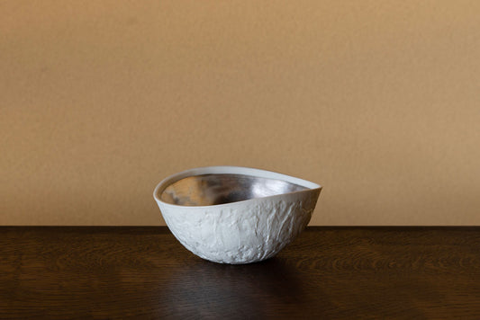 Small white ceramic bowl with a crumpled, irregular rim and a silver lining inside.