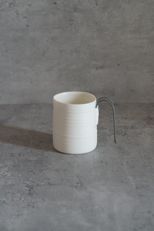 Tall white porcelain mug with fine horizontal ribbing and a thin dark wire handle.
