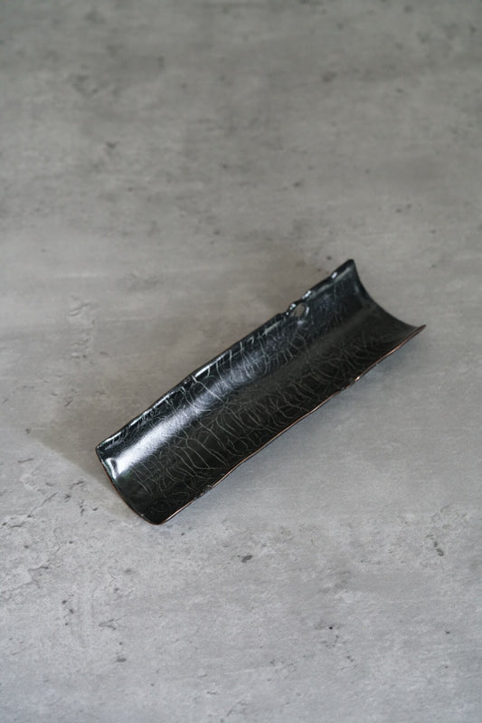 Long rolled tea scoop in dark enamel over copper, its surface flecked with silver.