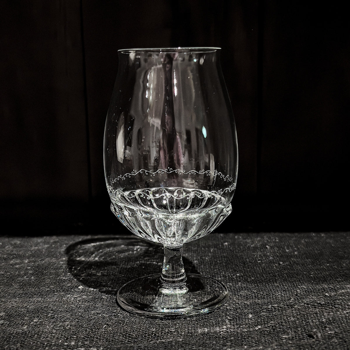 Tall footed glass with a tulip-shaped bowl, its lower half worked in a fine lace-like pattern.
