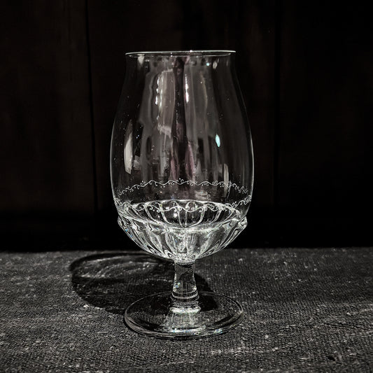 Tall footed glass with a tulip-shaped bowl, its lower half worked in a fine lace-like pattern.