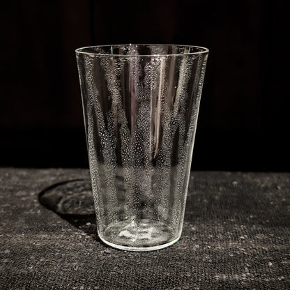 Tapered clear glass tumbler with a veil of tiny bubbles trapped through the glass.