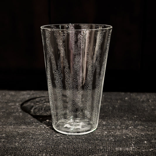 Tapered clear glass tumbler with a veil of tiny bubbles trapped through the glass.
