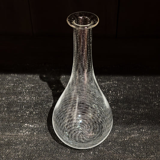 Tall clear glass vase with a bulbous base and a long slender neck, misted with fine bubbles.