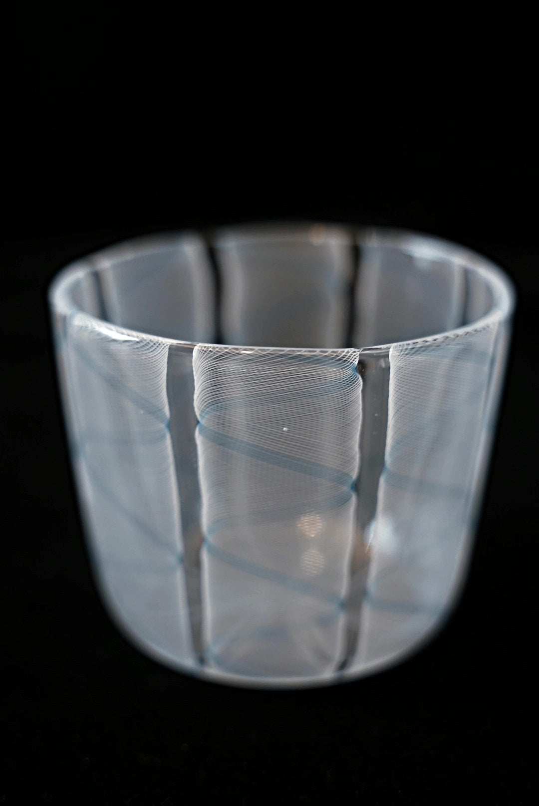 Clear glass cup wrapped in soft pale blue and white swirling stripes.