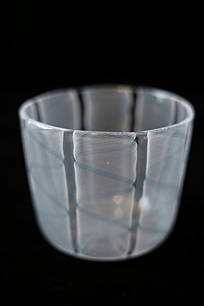 Clear glass cup wrapped in soft pale blue and white swirling stripes.